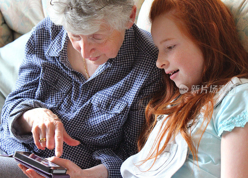 女孩向奶奶展示如何使用手机/智能手机图像